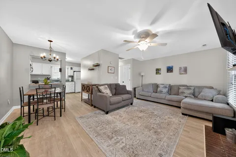a living room with furniture kitchen view and a chandelier