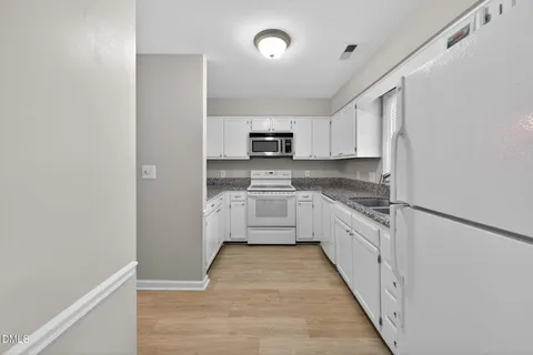 a kitchen with granite countertop a stove top oven sink and cabinets