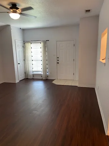 a view of an empty room with wooden floor and a window