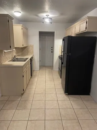 a kitchen with a sink a refrigerator and cabinets