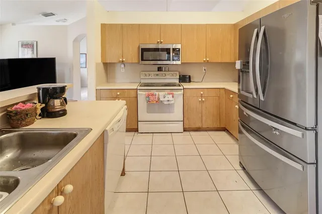 a kitchen with a sink a refrigerator and a stove top oven with wooden floor