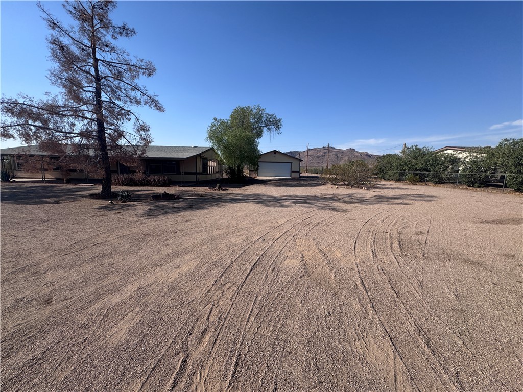 3053 McConnico Road Golden Valley, AZ 86413 - Photo 11 of 18 View of yard with dirt driveway, a garage, and a mountain view