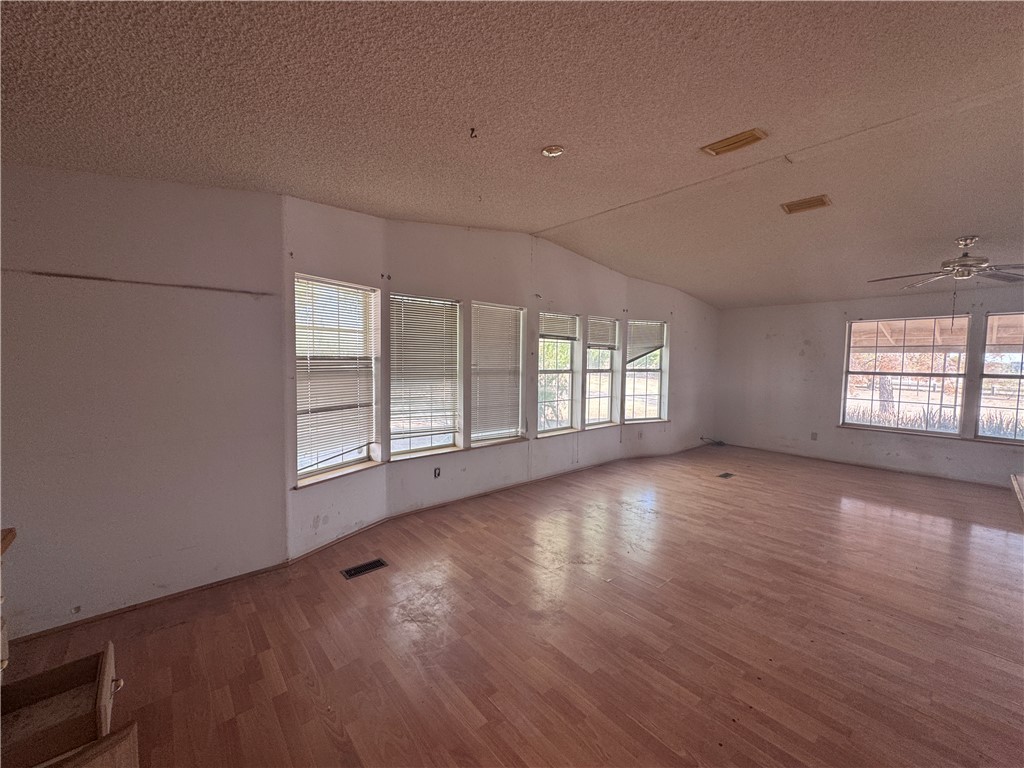3053 McConnico Road Golden Valley, AZ 86413 - Photo 16 of 18 Empty room with wood finished floors, vaulted ceiling, a textured ceiling, and a ceiling fan