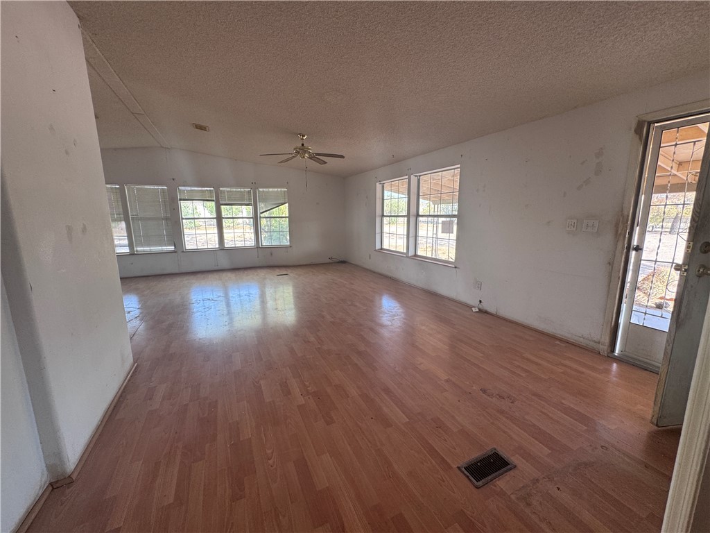 3053 McConnico Road Golden Valley, AZ 86413 - Photo 3 of 18 Empty room featuring wood finished floors, vaulted ceiling, a textured ceiling, and a ceiling fan
