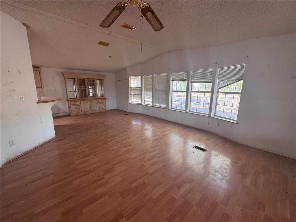 3053 McConnico Road Golden Valley, AZ 86413 - Photo 6 of 18 Unfurnished living room with a textured ceiling, wood finished floors, lofted ceiling, and ceiling fan