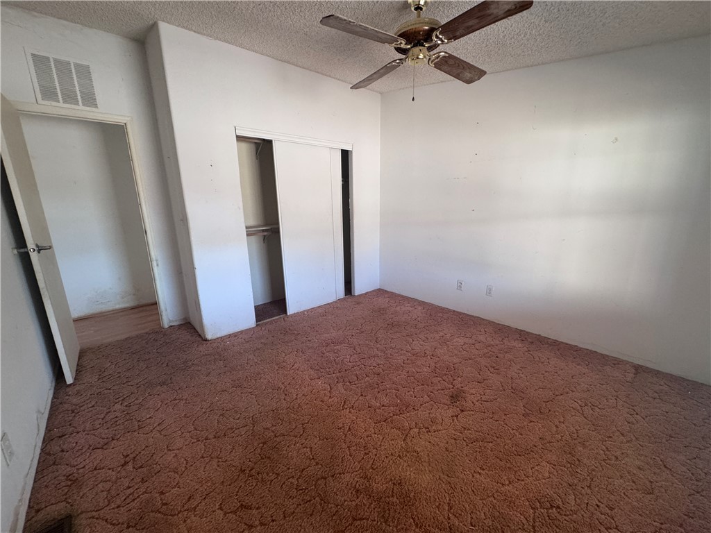 3053 McConnico Road Golden Valley, AZ 86413 - Photo 7 of 18 Unfurnished bedroom with carpet, a closet, a textured ceiling, and a ceiling fan
