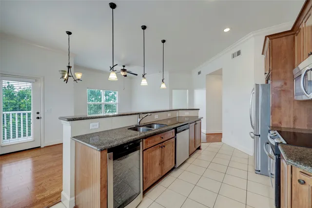 a kitchen with stainless steel appliances granite countertop a sink a stove and a wooden floor