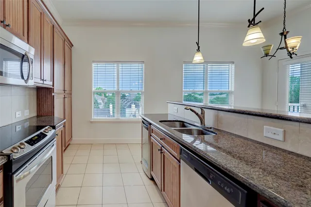a kitchen with granite countertop a sink a counter space appliances and cabinets