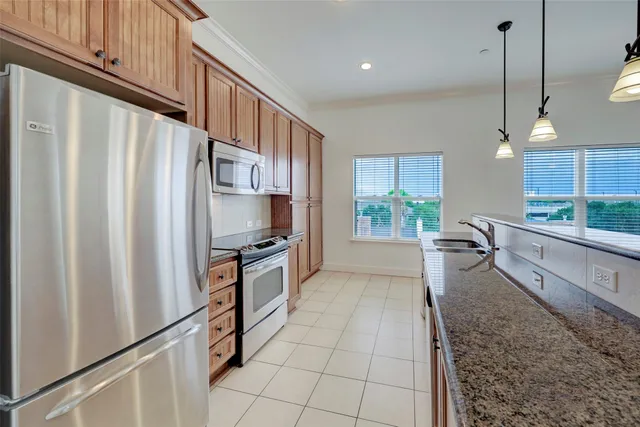 a kitchen with stainless steel appliances granite countertop a refrigerator a oven and a sink with granite countertops