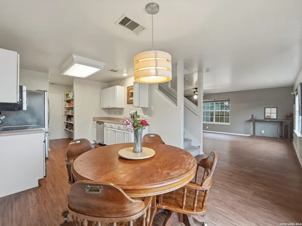 a dining room with wooden floor a chandelier a wooden table and chairs
