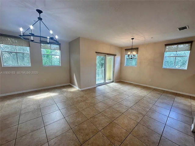 a view of a livingroom with a chandelier and kitchen view