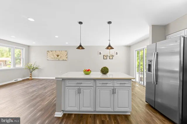 a kitchen with stainless steel appliances granite countertop a refrigerator a stove and a wooden floors