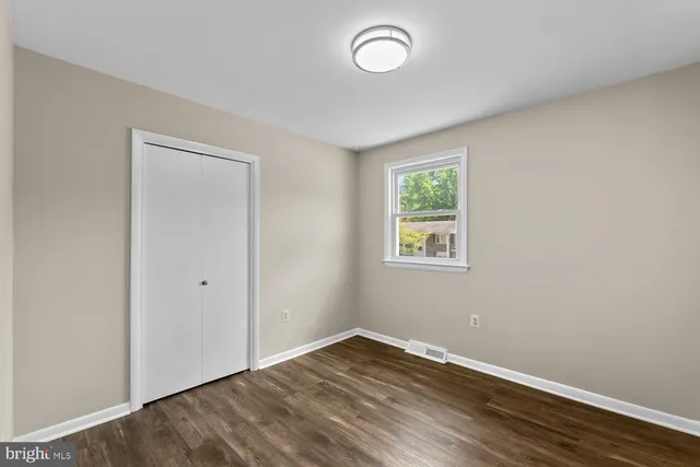 an empty room with wooden floor and window