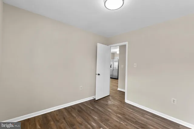 a view of an empty room with wooden floor and window