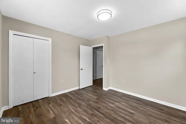 a view of an empty room with wooden floor and closet