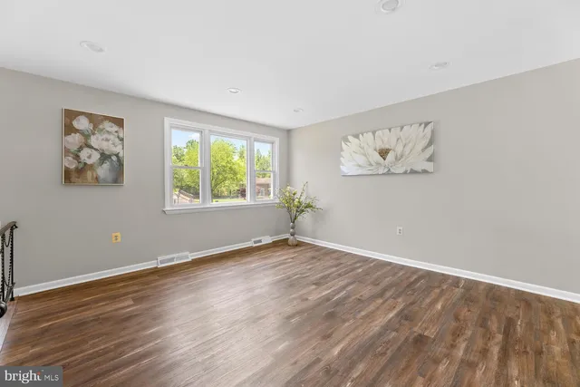an empty room with wooden floor and window