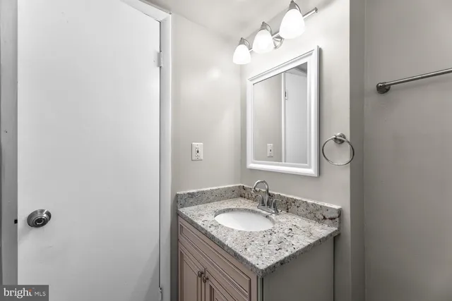 a bathroom with a granite countertop sink and a mirror
