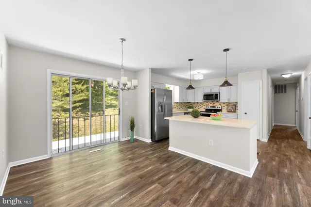 a kitchen with stainless steel appliances granite countertop a refrigerator a oven a kitchen island hardwood floor and a sink