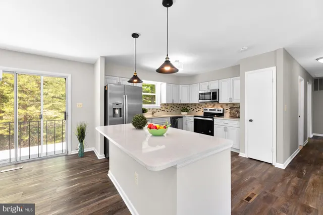 a large kitchen with lot of cabinets and wooden floor