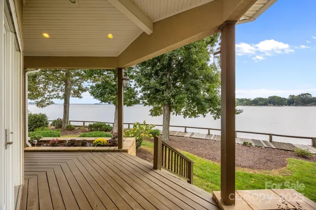 a view of a porch with wooden floor next to a yard