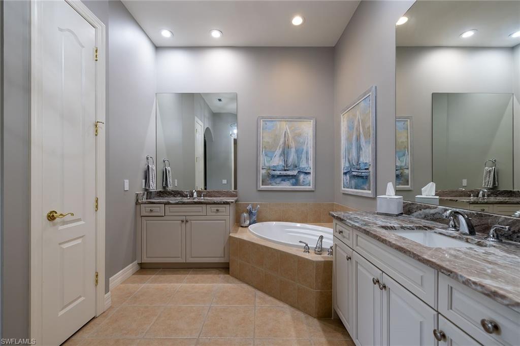 17066 Porta Vecchio Way, Unit 101 Naples, FL 34110 - Photo 21 of 32 a bathroom with a granite countertop double vanity sink a mirror and a bathtub