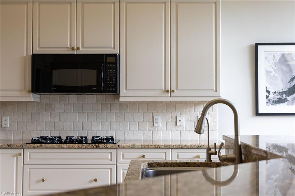 17066 Porta Vecchio Way, Unit 101 Naples, FL 34110 - Photo 29 of 32 a kitchen with granite countertop white cabinets and stainless steel appliances