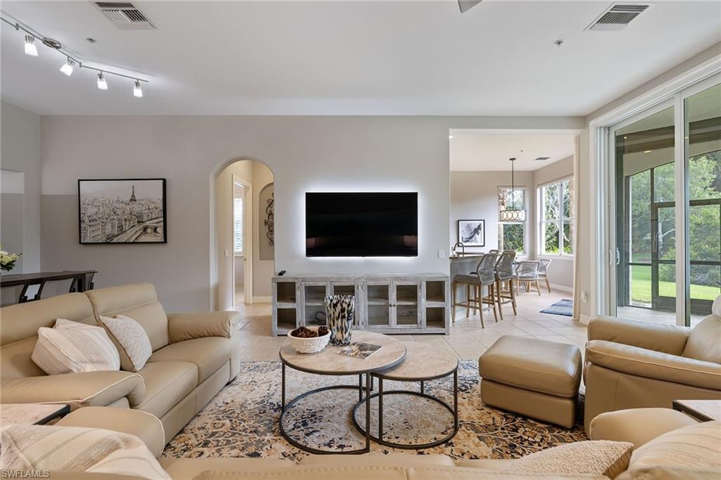 17066 Porta Vecchio Way, Unit 101 Naples, FL 34110 - Photo 4 of 32 a living room with furniture a flat screen tv and a large window