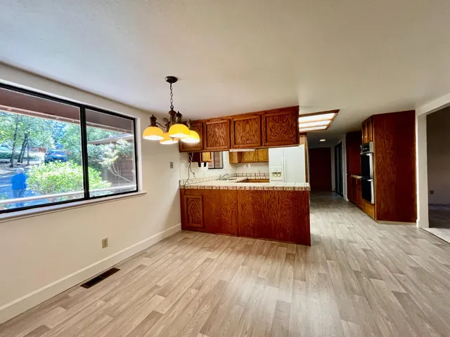 a kitchen with stainless steel appliances granite countertop a refrigerator a sink dishwasher a stove and a dining table with wooden floor