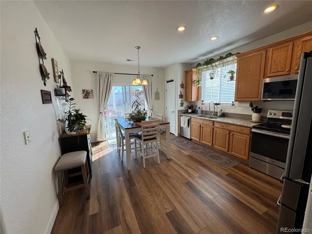 a kitchen with stainless steel appliances granite countertop a stove top oven a sink dishwasher a dining table and chairs with wooden floor