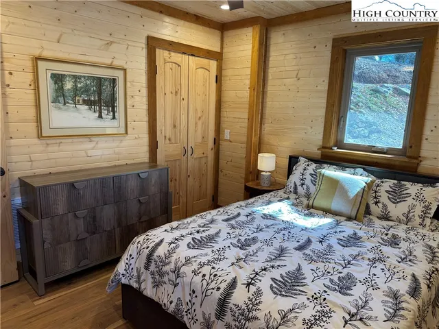 a bedroom with a bed a dresser and wooden floor