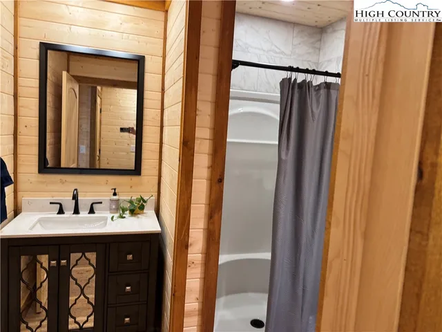 a bathroom with a sink a mirror a vanity and a shower