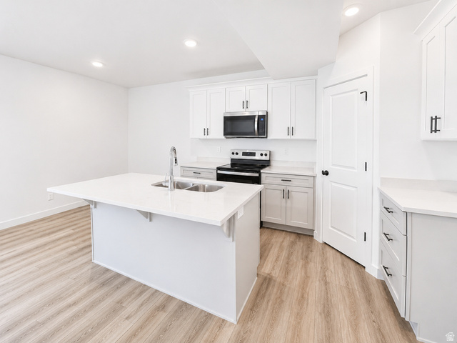 1004 West Paramount Cove South, Unit 315 Ogden, UT 84405 - Photo 29 of 42 Basement ADU kitchen featuring white shaker cabinetry, light-toned wood-finish flooring, recessed lighting, and a kitchen island with an undermount double-basin sink