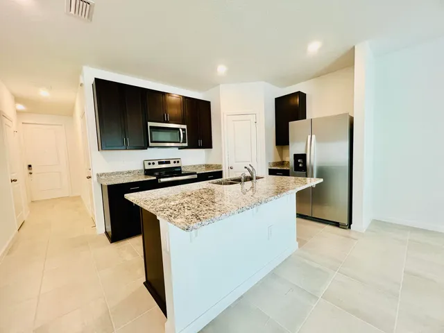 a kitchen with stainless steel appliances granite countertop a sink a stove and a refrigerator