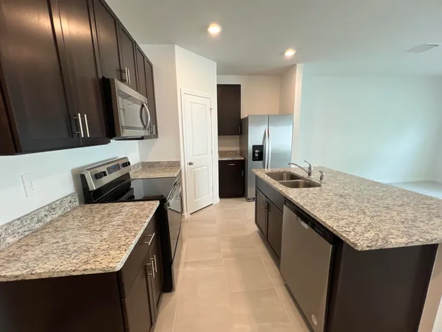 a kitchen with stainless steel appliances granite countertop a sink stove and refrigerator