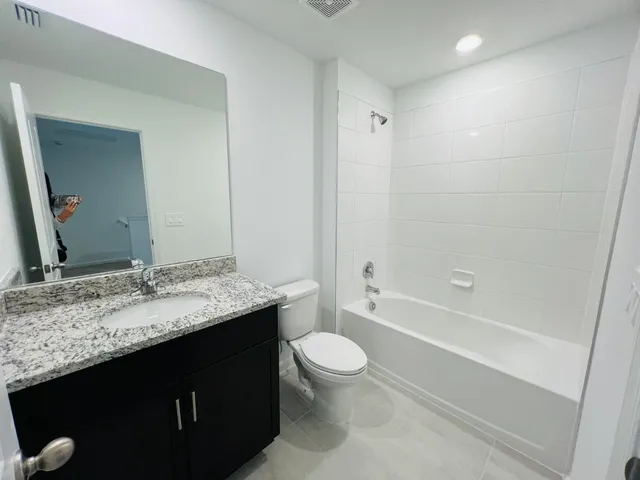 a bathroom with a granite countertop sink toilet a large mirror a bathtub and shower