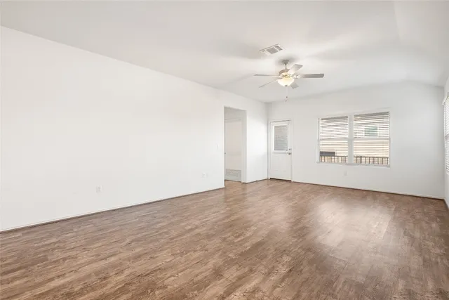 an empty room with wooden floor and windows