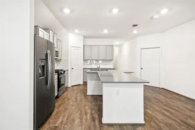 a kitchen with stainless steel appliances a sink stove refrigerator and white cabinets