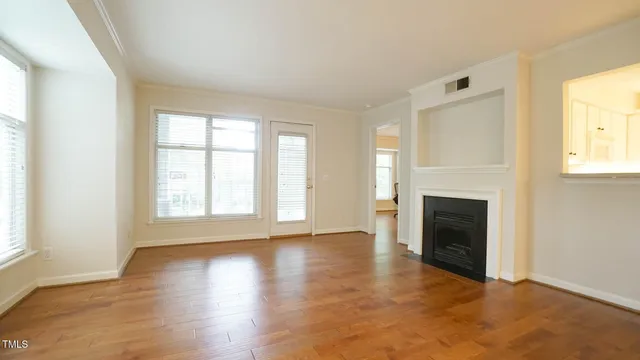 an empty room with windows a fireplace and wooden floor