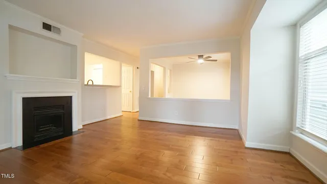 a view of an empty room with a window and wooden floor