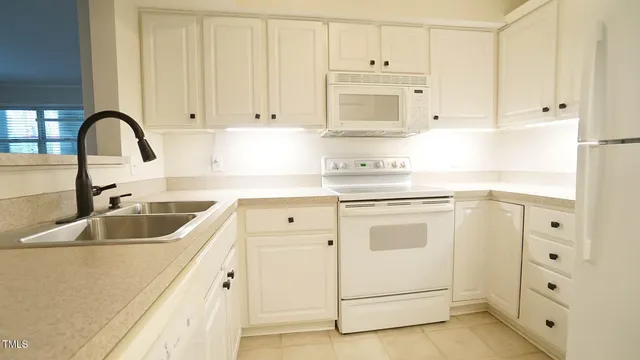 a kitchen with white cabinets and white appliances
