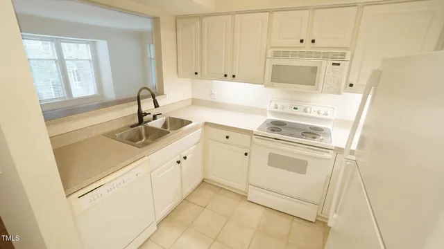 a kitchen with white cabinets and white appliances