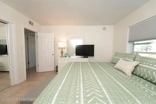 a spacious bedroom with a bed and a flat screen tv