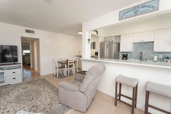a living room with furniture a flat screen tv and kitchen area