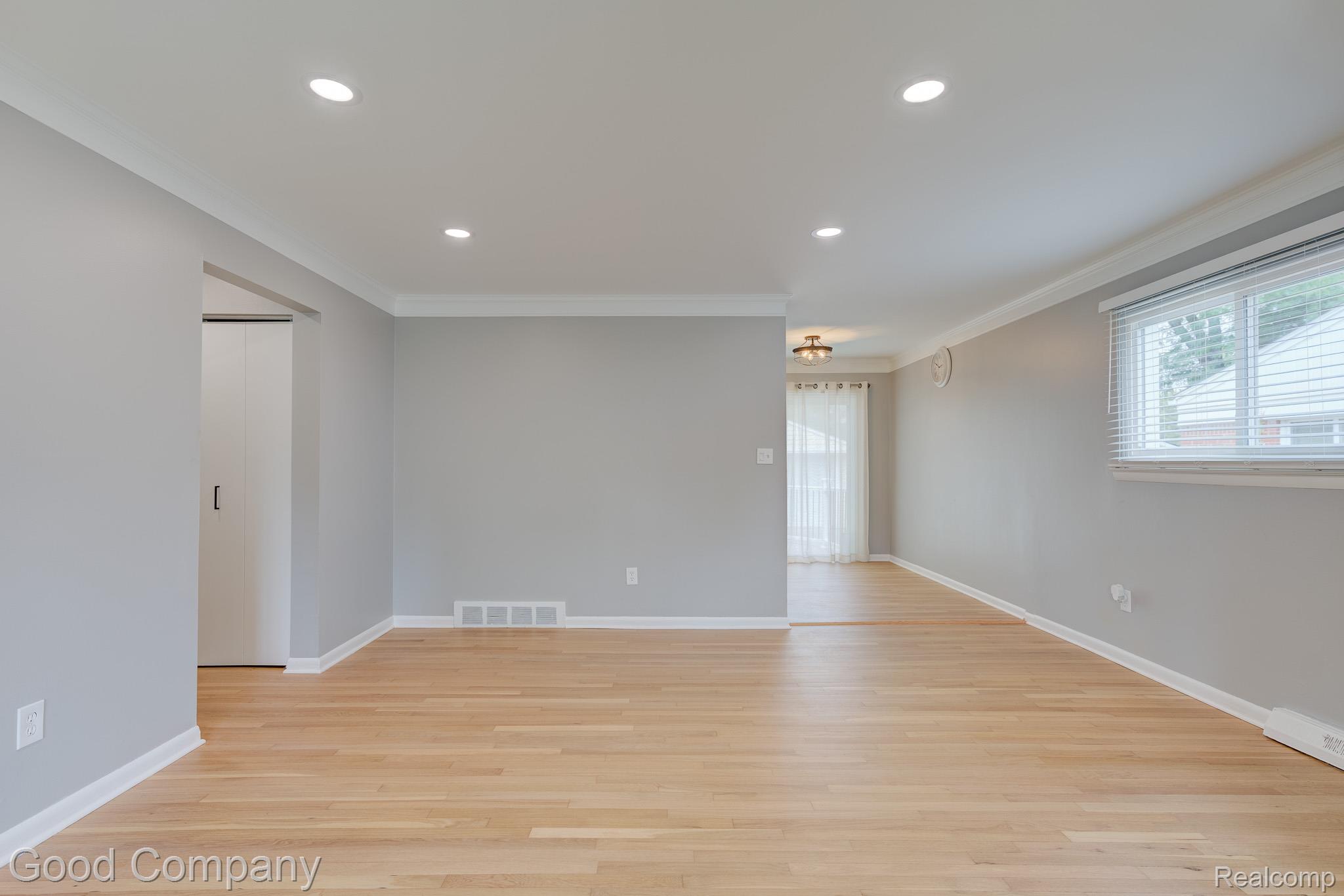 Recessed lighting, light wood-finish flooring, neutral wall tones, white trim, and a window with blinds