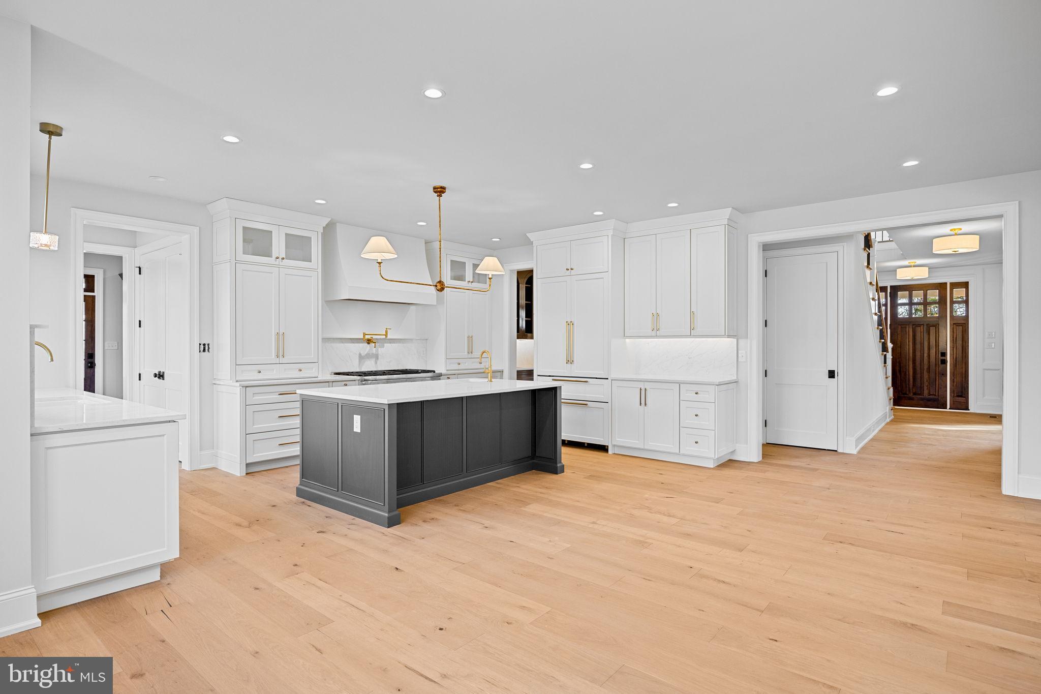 16 Fariston Road Wayne, PA 19087 - Photo 26 of 106 a large white kitchen with kitchen island a refrigerator a sink dishwasher and white cabinets with wooden floor