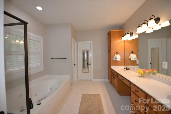 a spacious bathroom with a tub sink and mirror