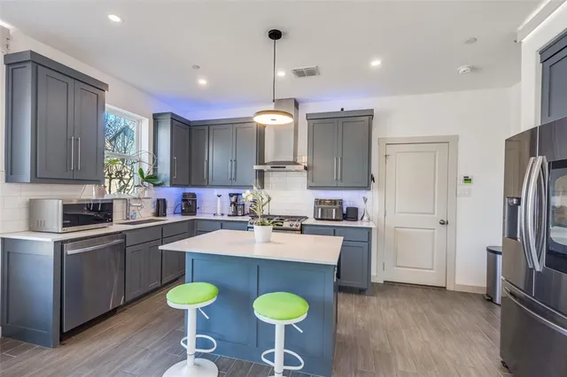 a kitchen with refrigerator a sink and chairs