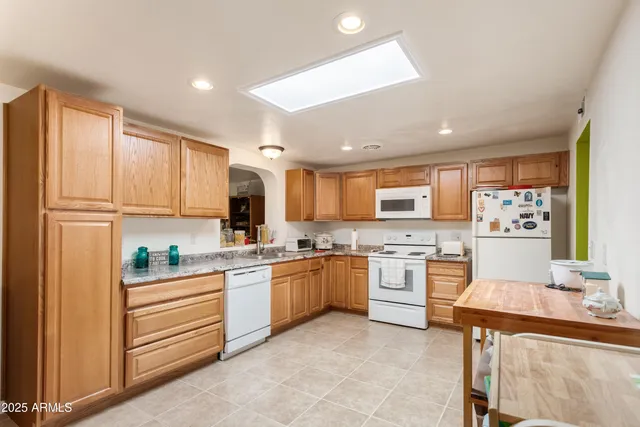 a kitchen with stainless steel appliances granite countertop a stove top oven a sink dishwasher and a refrigerator with wooden floor