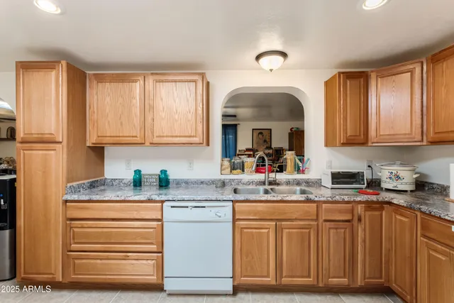 a kitchen with granite countertop a sink cabinets stainless steel appliances and a window
