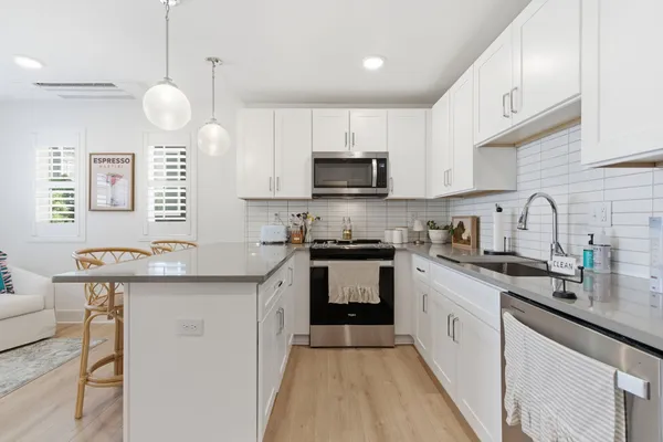 a kitchen with a sink a counter top space cabinets and stainless steel appliances